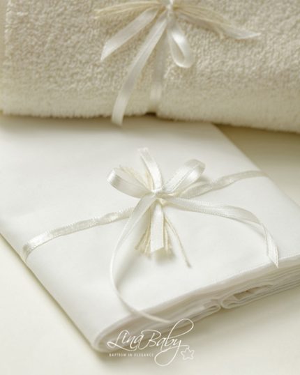 White towels and a neatly folded white cloth tied with satin ribbons, arranged as a soft spa gift set on a light surface.