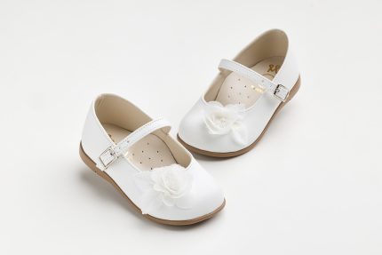 White kids' Mary Jane shoes with a fabric flower on the toe and buckled straps, shown on a light background