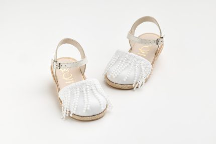 Toddler white sandals with beaded fringe across the front and a beige ankle strap on a white background, photographed from above left.