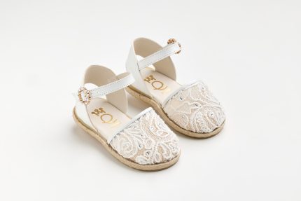 White lace espadrille sandals for a child with decorative crystals and white ankle straps on a light background