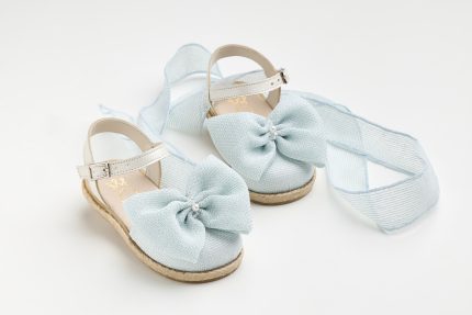 Light blue baby sandals with large fabric bows and beige ankle straps on a white background.