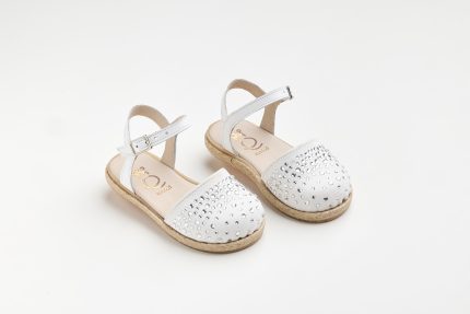 White sandals for kids with rhinestone-studded front strap and ankle buckle, on a light background