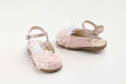 Pink girls' sandals with flower embellishments and white feathers on a light background, showing decorative design details in a pair.