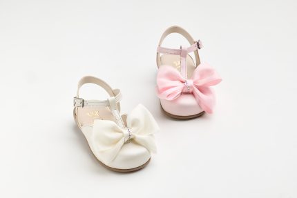 Three pastel-colored children's dress shoes with large fabric bows and rhinestone details on a white background.