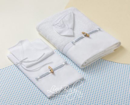 Two white baby garments neatly folded with tie closures, placed beside a folded towel on a pale, dotted blue mat, suggesting a baby gift set.