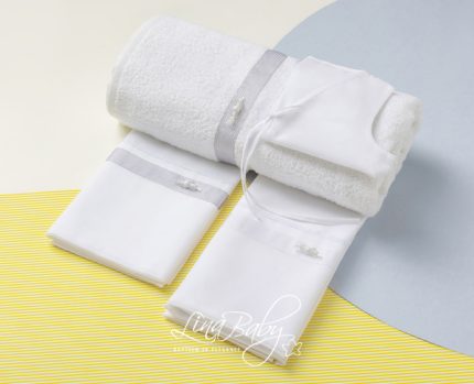 Set of white towels and washcloths with gray borders folded and rolled on a yellow-striped surface