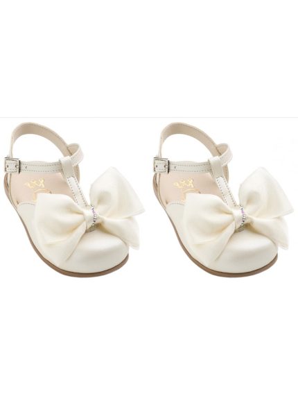 Two white satin baby sandals with large cream bows on each shoe and ankle straps, shown side by side on a white background.