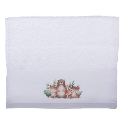 White folded towel with a decorative band showing a cartoon family of woodland animals (bear, foxes) and greenery on the lower portion