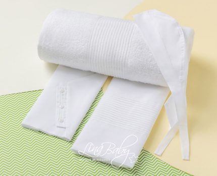 White rolled towel with robe belt and cuffs laid on a green chevron mat.