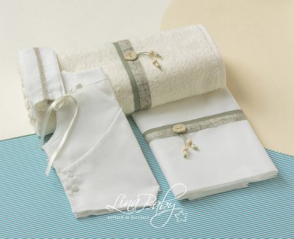 White towel set with matching robes and washcloths, accented by green ribbons and wooden beads, laid on a blue striped surface