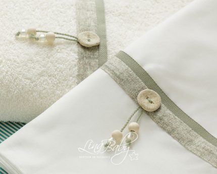 Soft cream towel and white baby blanket with taupe trim and wooden buttons, accented by pale beads; Ling Baby logo visible on fabric.