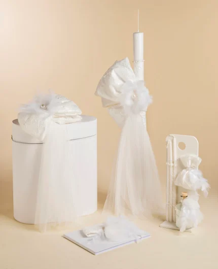 White wedding decor set featuring a tall pillar candle with tulle, a round white box with draped fabric, feather accents, and a white card/book display.