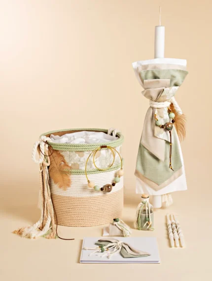 Boho-style home decor set with a woven rope basket, folded textiles, beads, tassels, and a tall pillar candle on a stand, all in beige and sage tones.