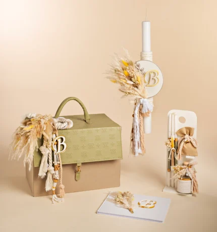 Beige decorative scene with a monogrammed B box, tassels, dried grasses, and a tall candle in a neutral setting.