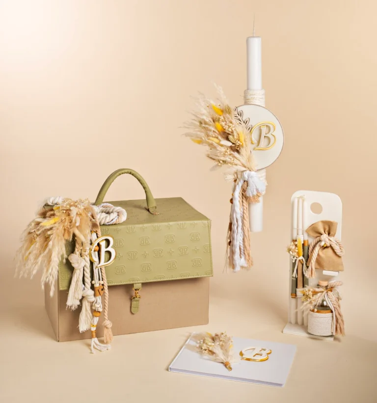 Beige decorative scene with a monogrammed B box, tassels, dried grasses, and a tall candle in a neutral setting.