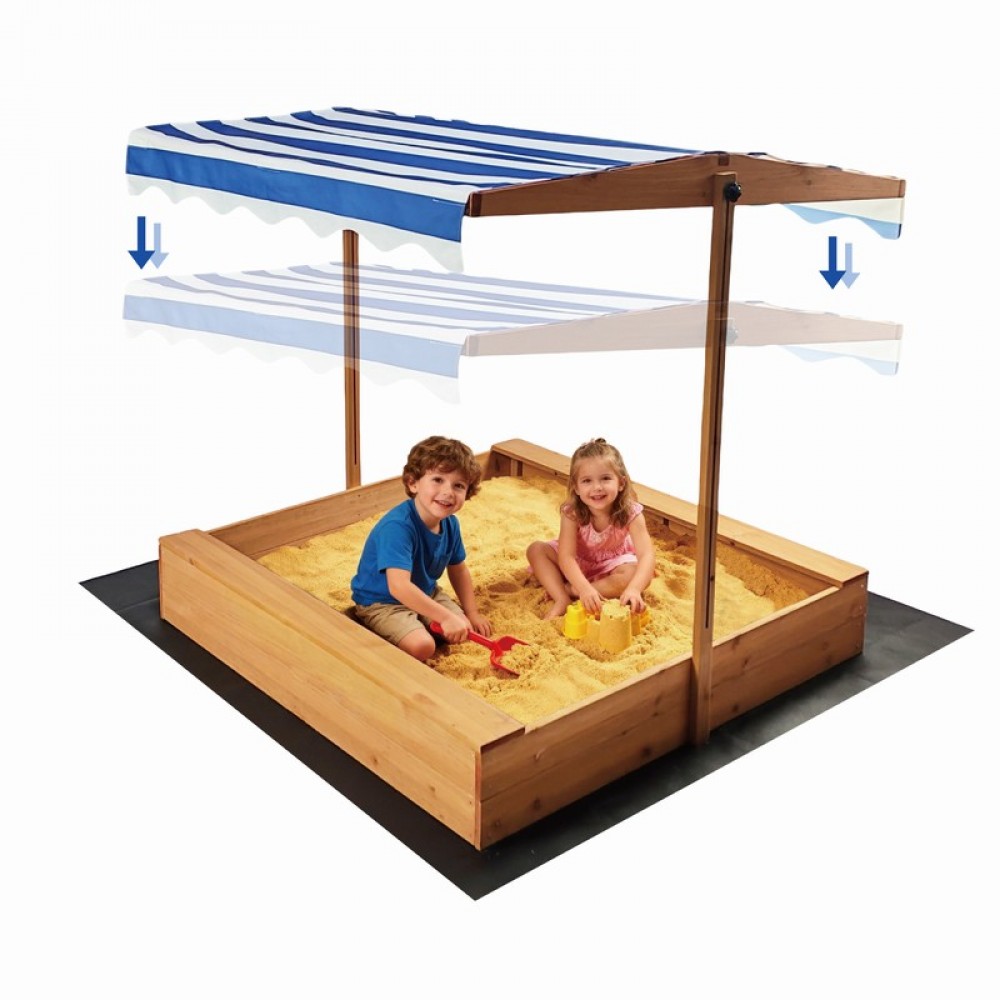 7462562-1000x1000 Children play in a wooden sandbox with a blue-and-white striped canopy, sitting in sand with toy buckets and shovels.