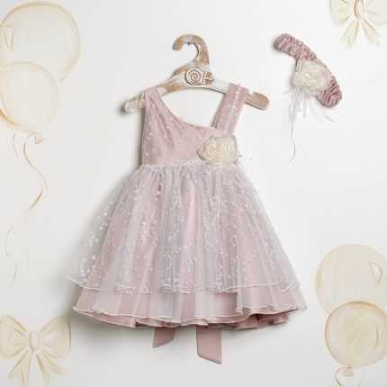 Pink toddler dress with tulle overlay and floral waist detail on a wooden hanger, plus a matching pink headband with a white flower nearby.