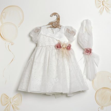 White baby/flower girl dress with puff sleeves and a delicate tulle overlay, decorated with pink fabric roses at the waist, on a wooden hanger. A matching veil with a pink rose sits beside it on a white background.
