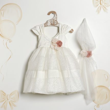 White baby dress with glittery striped layers and a pink fabric flower, hanging on a wooden hanger; matching veil with a pink flower on the side.