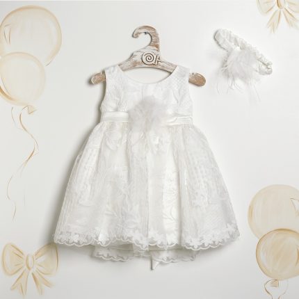 White lace baby dress on a wooden hanger with satin sash and floral hem, shown against a light backdrop with balloons.