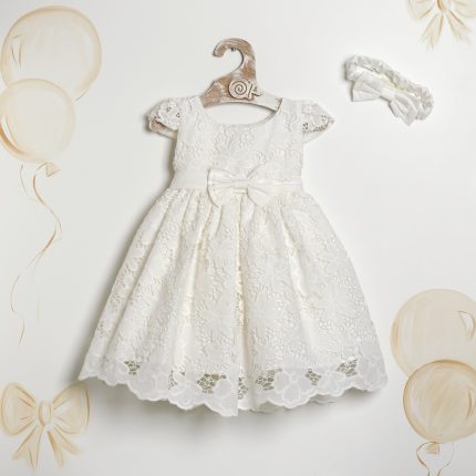 White lace dress with a satin bow at the waist hanging on a wooden hanger.