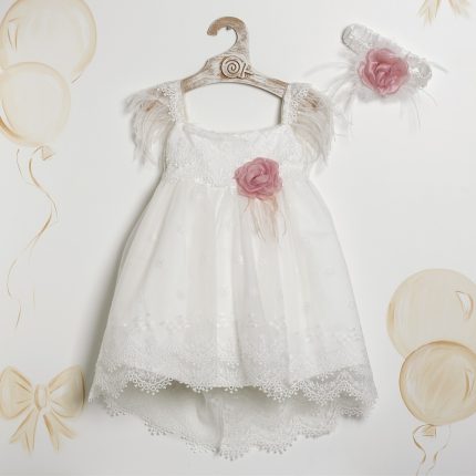 White lace dress on a wooden hanger with pink flower accents and feather sleeves, plus a matching headband nearby.