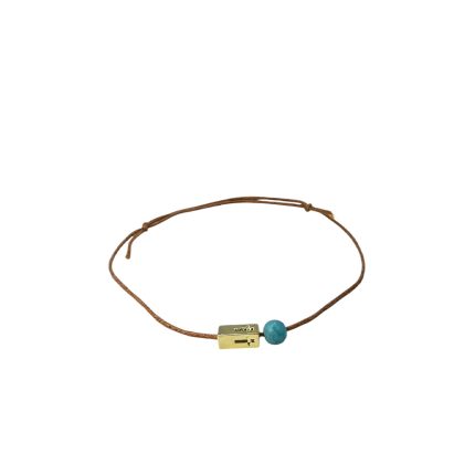 Brown cord bracelet with a small gold clasp and a turquoise bead, worn as a simple jewelry accessory