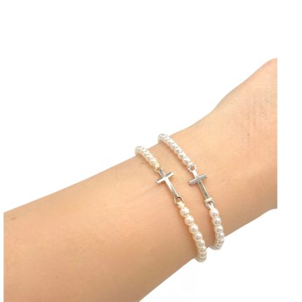 Two pearl bead bracelets with silver cross charms on a wrist.