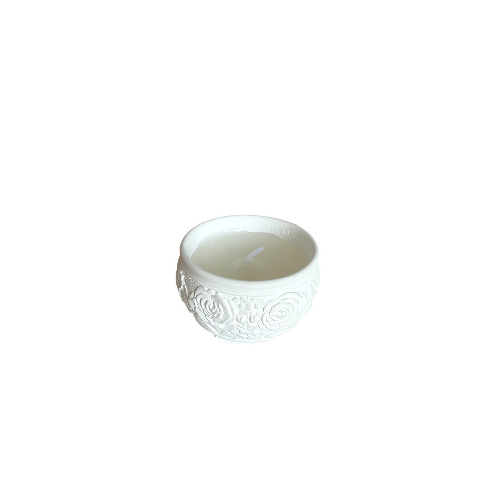 20582BCC-C6F4-0AE8-3856-019F471AB4C8_11 | La Vie en Rose White ceramic votive holder with raised rose pattern and a small white candle inside.