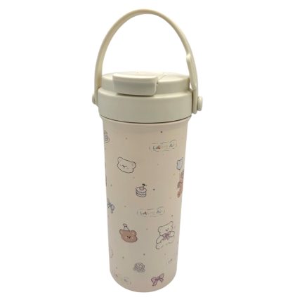 Cream-colored plastic tumbler with a flip-top lid and a cute bear and cake print pattern, plus a white handle.