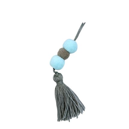 Gray tassel ornament with two pale blue beads and a brown bead along a cord, photographed diagonally against a white background.
