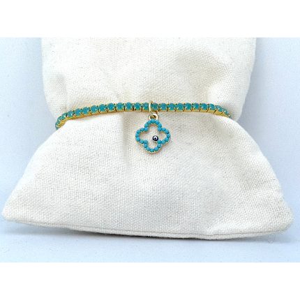 Turquoise beaded bracelet with gold setting and a four-leaf clover charm featuring a tiny blue eye bead, displayed on a white fabric cushion.