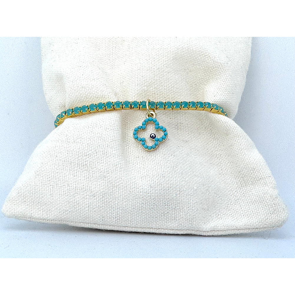 66D9A84E-67A9-6ACF-2F13-01866F7BA513_21 | La Vie en Rose Turquoise beaded bracelet with gold setting and a four-leaf clover charm featuring a tiny blue eye bead, displayed on a white fabric cushion.