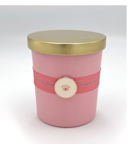 Pink cylindrical container with a gold lid, wrapped by a pink ribbon featuring a round cream charm with an eye motif.