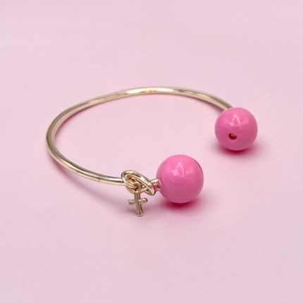 Open silver bracelet with two pink beads and a small female symbol charm, set on a pale pink background.