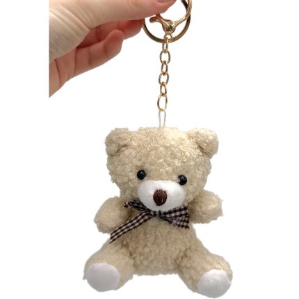 Cream teddy bear keychain with brown plaid ribbon hanging from a gold chain.