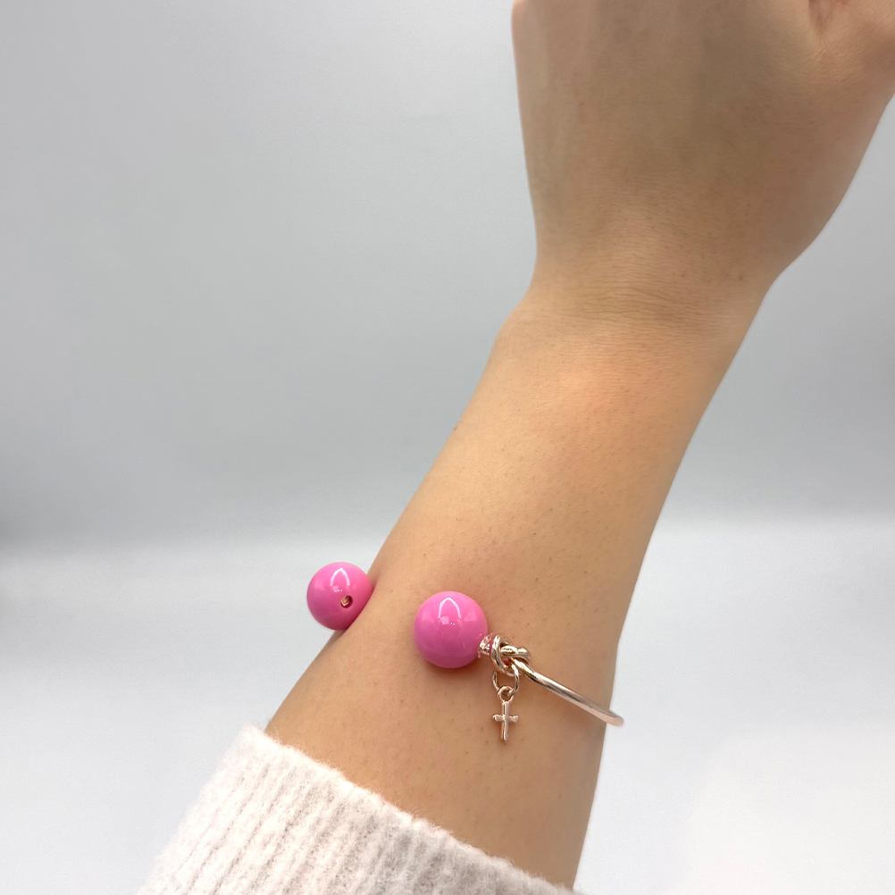 A8D34FA3-009C-79FA-0F4D-019C2E457AAE_21 | La Vie en Rose Pink bead bracelet with a small cross charm on a light-skinned wrist.