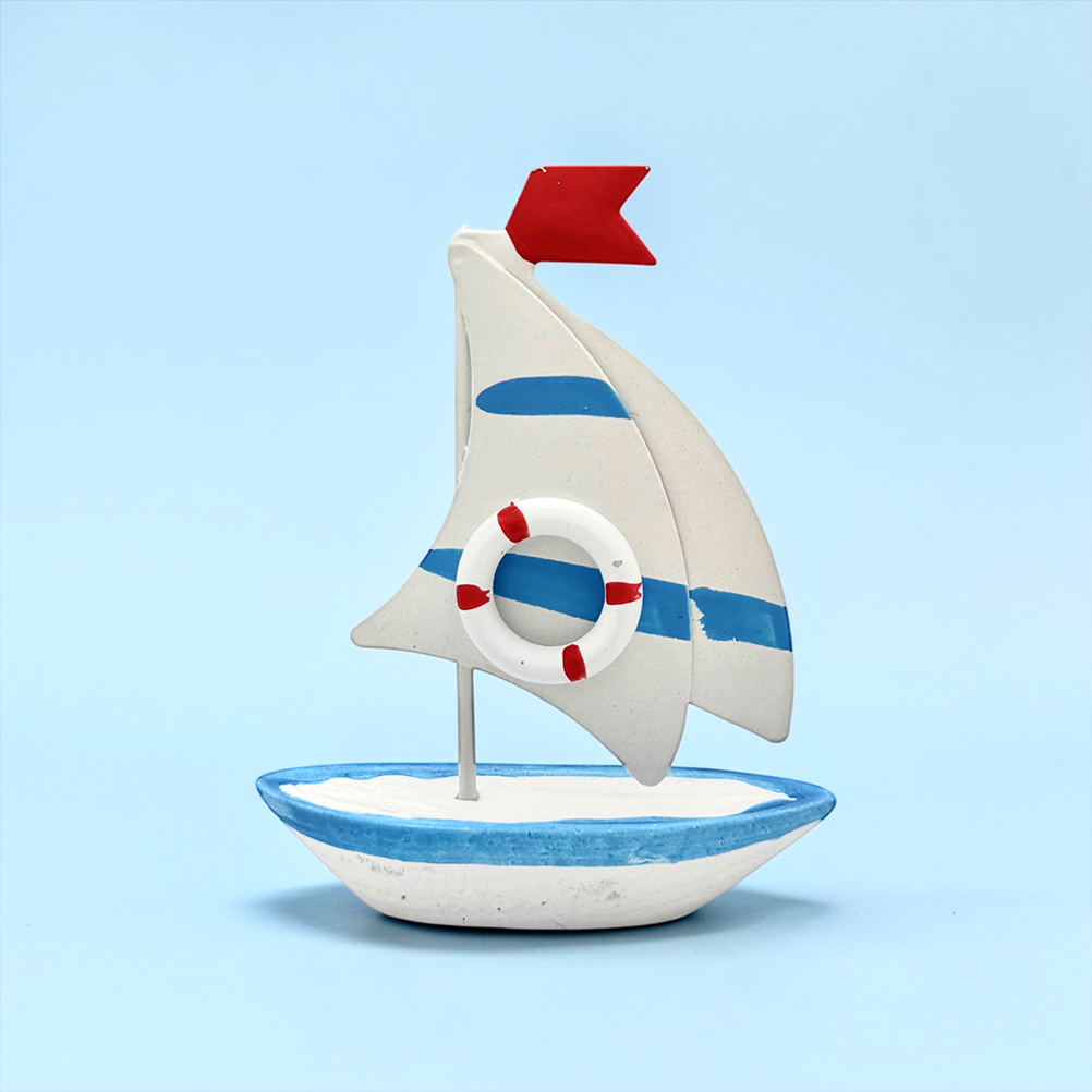 B75EA66E-610B-F4CA-EA28-019D013FA99D_11 | La Vie en Rose Decorative ceramic sailboat figurine with a lifebuoy, blue stripe, and red flag on a light blue background.