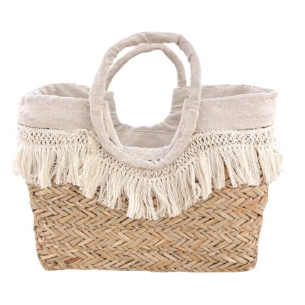 Woven straw tote bag with a cream fabric top and fringe trim along the edge, two rounded handles made of fabric.
