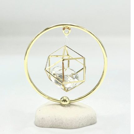 Gold circular frame with a suspended geometric wireframe cube holding a crystal, mounted on a white stone base (decorative gift ornament).