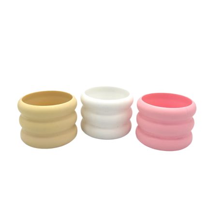 Three pastel ribbed silicone sleeves in yellow, white, and pink lined up in a row.