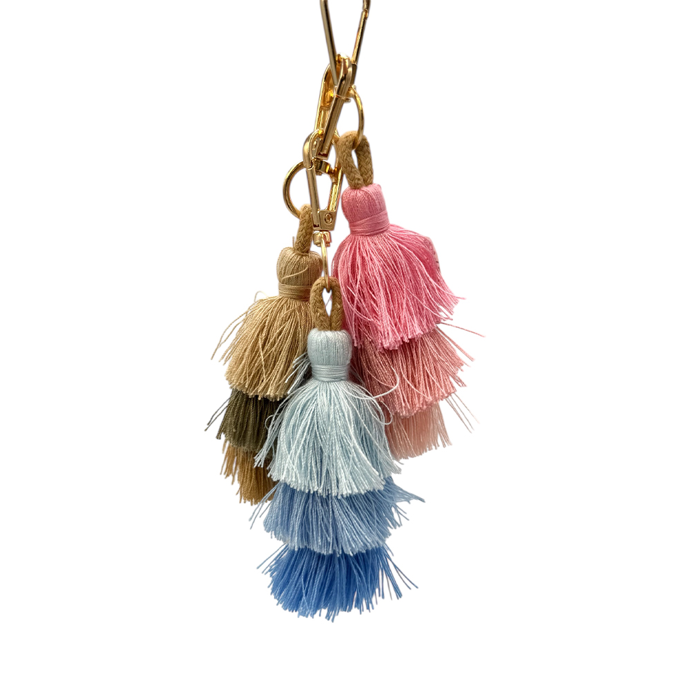 F559C162-3AE4-6BAE-CE18-019D05638760_31 | La Vie en Rose Colorful tassel keychain charm with five tassels in pink, beige, light blue, blue, and olive hanging from a gold chain.