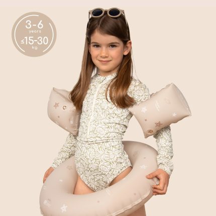 Young girl in a beige floral swimsuit wearing beige inflatable arm floaties and sunglasses, posing against a pale background. The left circle shows age 3–6 years and weight up to 15–30 kg.