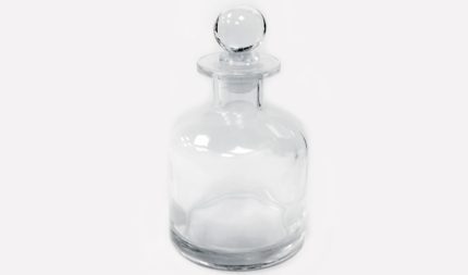Clear glass bottle with a round stopper, empty.