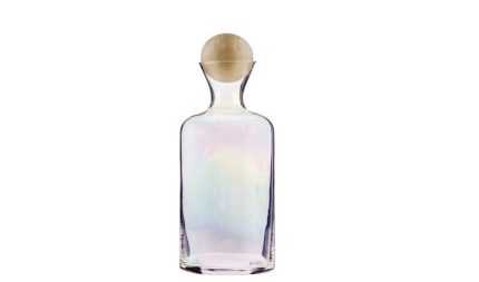 Transparent glass perfume bottle with an iridescent pastel liquid and a round wooden stopper, set against a white background.