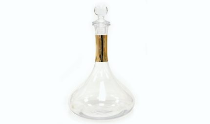 Clear glass decanter with a round stopper and a gold-toned neck, empty and elegant.