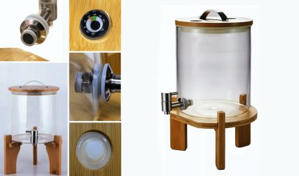 Large glass beverage dispenser on a wooden stand with a metal spigot and gold-toned lid.