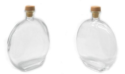 Two empty clear glass bottles with wooden cork stoppers, leaning apart on a white background