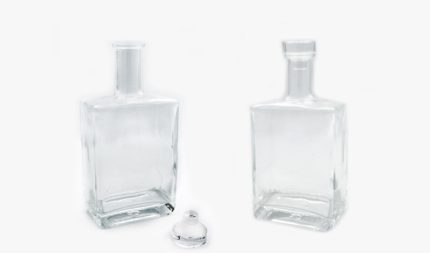 Two empty clear glass bottles with stoppers on a white background, side by side at a slight angle.