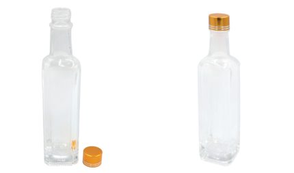 Two empty clear glass bottles with orange caps, one standing upright with its cap off resting nearby on the left side.